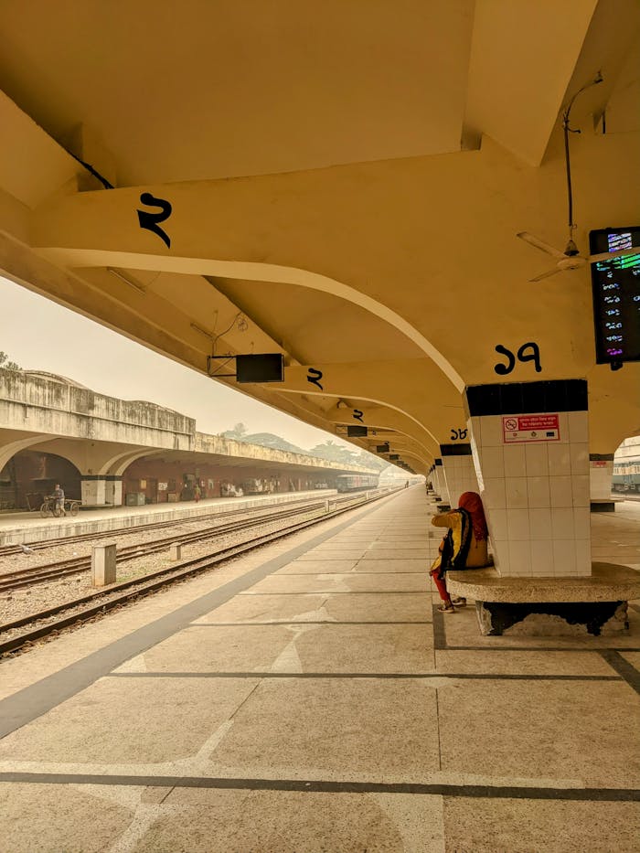 about-us A solitary figure sits at Dhaka Railway Station, embodying peaceful reflection.