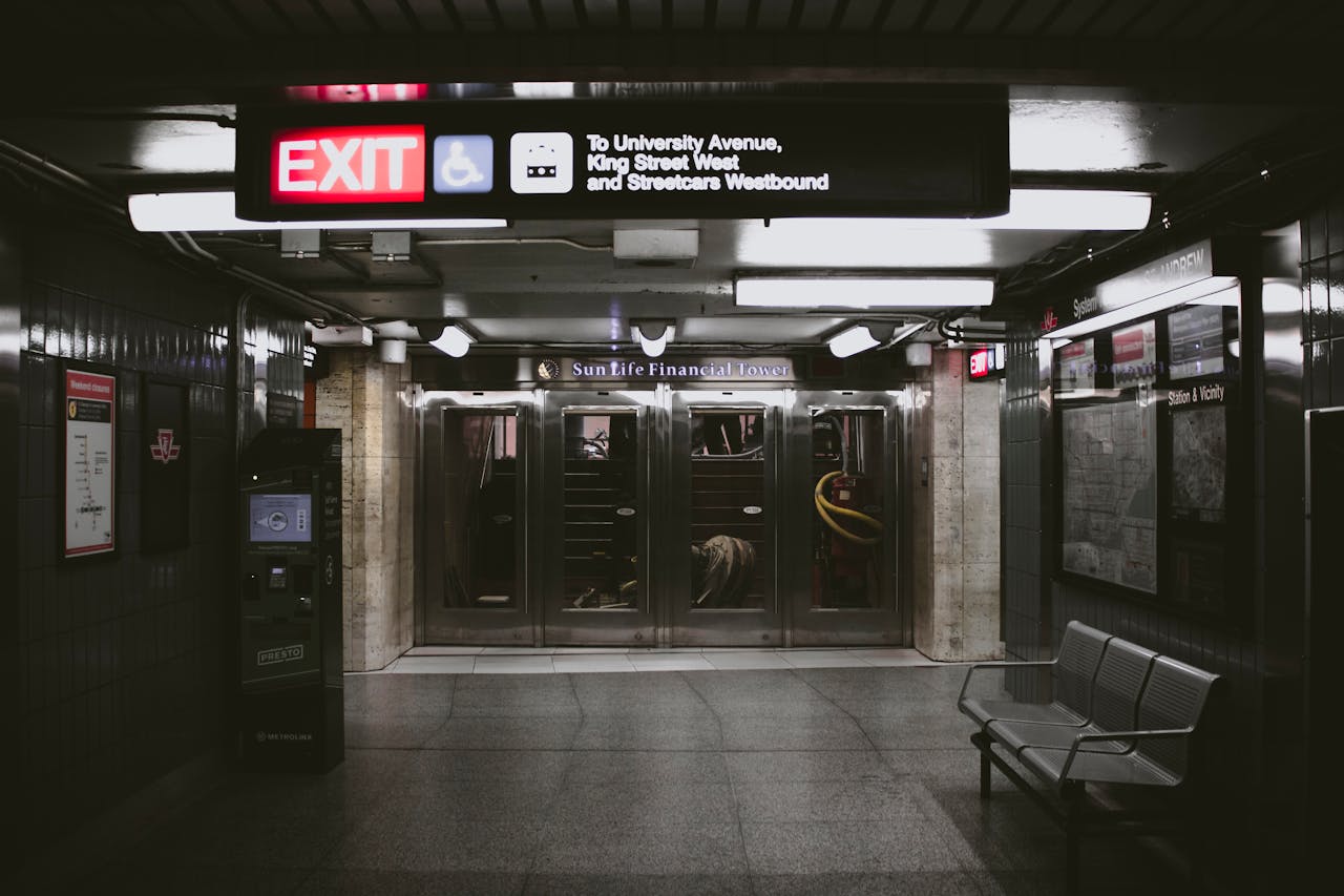 services-02 Dark and empty view of a Toronto subway station with exit signs and seating area.